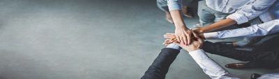 Six people in a half circle hands in the middle on top of each other